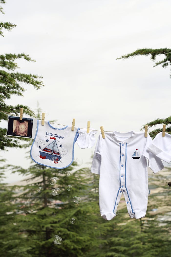 Cute baby items including a bib, romper, and ultrasound photo hanging on a clothesline.