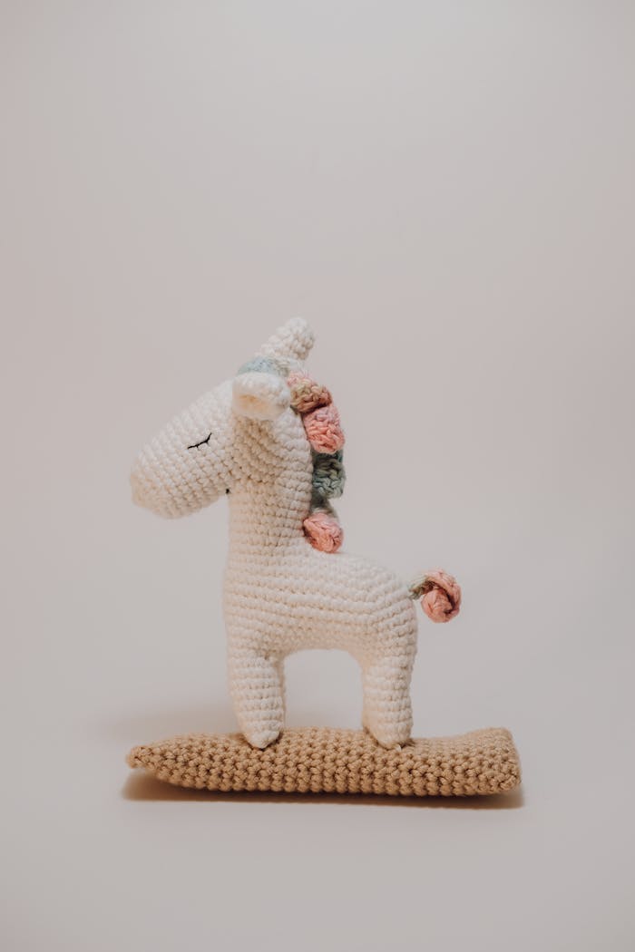 A charming handmade crochet unicorn toy with pastel decorations, perfect for children's rooms.